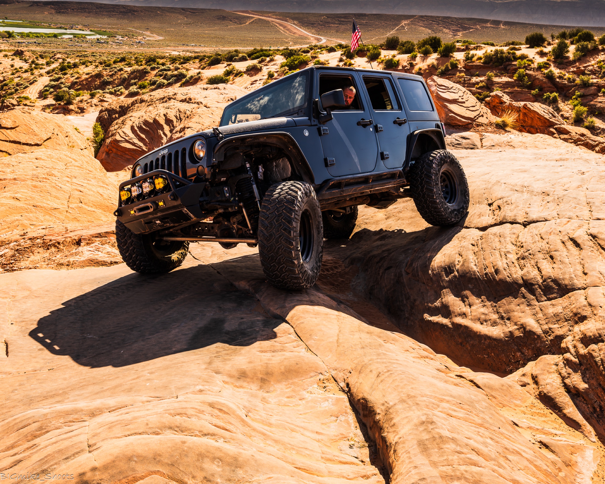 Jeep flexing on slickrock with the flag flying
